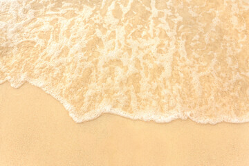 Soft wave foam of ocean on sandy beach background