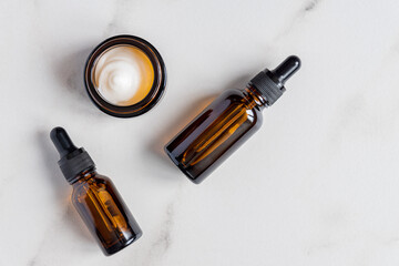 anti-aging collagen facial serum in dark glass bottle and face cream on marble background with copy space. Natural Organic Cosmetic Beauty Concept
