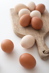 white and brown eggs lie on a wooden board on a white table. home life. The process of preparing for Easter.