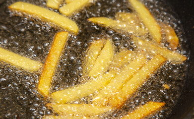 French fries are fried in oil in a pan.