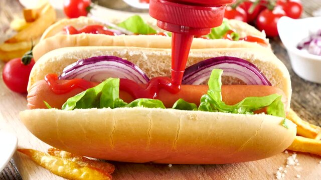 ketchup pouring on hot dog with sausage