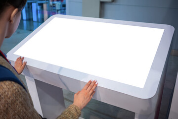 White screen, mock up, future, copyspace, template, technology concept. Woman looking at blank interactive touchscreen white display of electronic kiosk at futuristic exhibition or museum