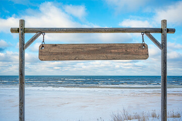Wooden sign with copy space against blue sky and sea with waves background. Blank wooden sign.
