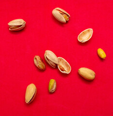 Close-up of fresh pistachio nuts on a red background.