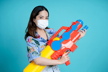 Asian woman wear mask and play with water gun in Songkran Festival.