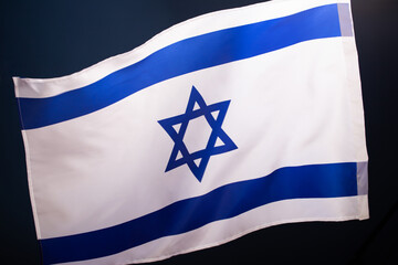 Israel flag waving against clean blue sky, close up.
