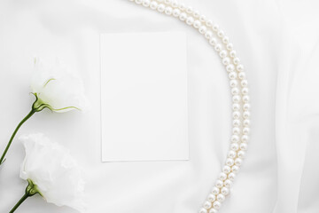 Wedding invitation, white rose flowers and pearls on silk fabric as bridal flatlay background,...