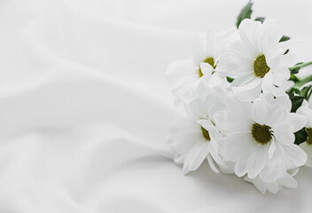 White daisy flowers on silk fabric as bridal flatlay background, wedding invitation and holiday...