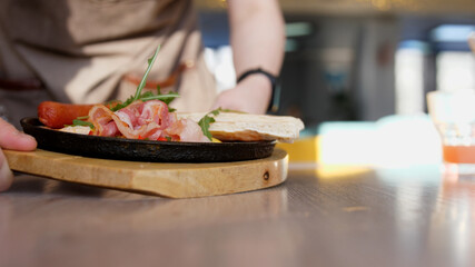 Waiter Serving Food in Fried Pan of shakshuka in Restaurant in breakfast time. Close Up View
