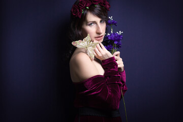 Studio shot of spring woman with butterfly and bouquet of blue flowers