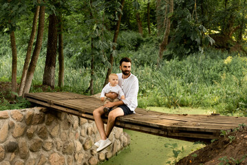 Fototapeta premium Happy man playing with his baby son outside on a sunny day