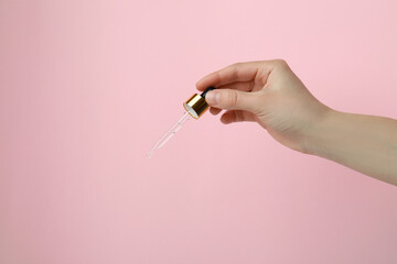 Female hand hold pipette with pine oil on pink background