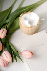 Obraz na płótnie Canvas Cappuccino cup with planner and blush pink tulips. Work from home concept