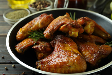 Concept of tasty food with baked chicken wings on wooden background