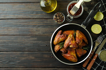 Concept of tasty food with baked chicken wings on wooden background, space for text