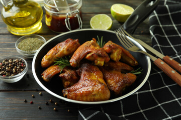 Concept of tasty food with baked chicken wings on wooden background