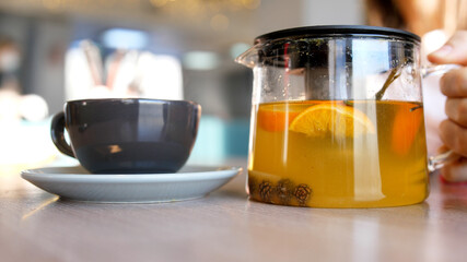 Woman s hands put a pot with hot tea on a wooden table. 4k