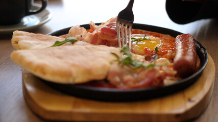 Eating Shakshuka Poached Eggs with Tomato and Bread Served in a Frying Pan. Israeli Arab Middle...
