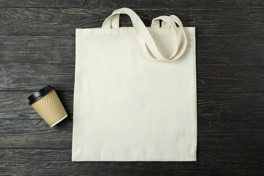 Eco bag and paper cup on wooden background, space for text