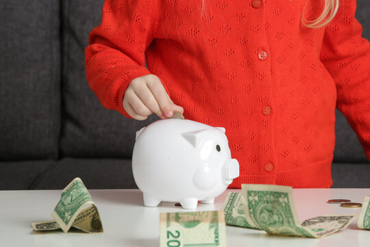 Little Girl Putting Money Into Piggy Bank. Child Learning About Financial Responsibility And Savings.