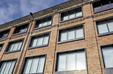 Brick building with windows and downspout against blue sky