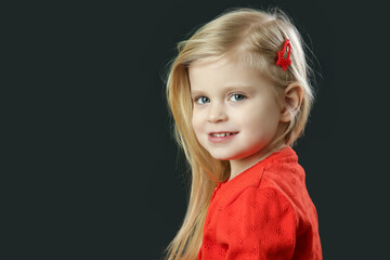 Studio portrait of beauiful blonde toddler girl in red cardigan