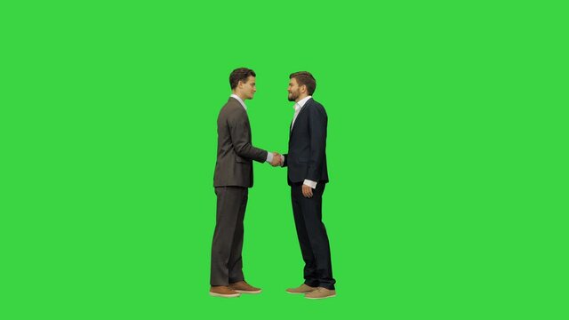 Two young and handsome business partners in suits meet and shake hands, full size video on a Green Screen, Chroma Key.