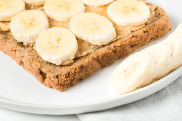 Homemade peanut butter sandwich with bananas and honey on wooden background.