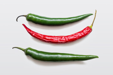 Green and red hot chili peppers on white background