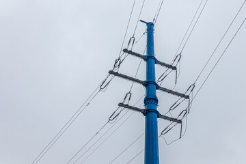 High-voltage power line in blue, against a rainy sky