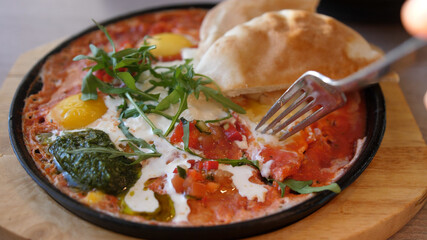 Eating Shakshuka Poached Eggs with Tomato and Bread Served in a Frying Pan. Israeli Arab Middle Eastern Cuisine. 4k