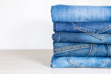 Denim trousers folded in a pile on a store window.