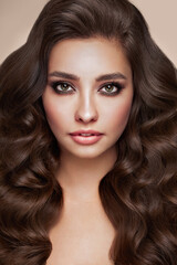 Fototapeta premium Brunette girl with perfect makeup. Smiling beautiful model woman with long curly hairstyle. Care and beauty hair products