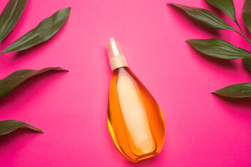 Suntan oil on a pink background . Suntan oil and green leaves. Vacation. Protect your skin from the sun. Uniform tan. Article about vacation. Article about packing for vacation. Pink background. Copy 