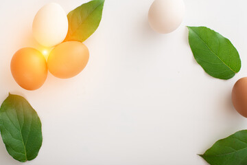 Easter decoration in the form of a round wreath of white and brown eggs and green leaves on a white background. place for text. copy space. flat lay