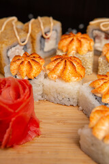 Big sushi set on light wooden dish isolated on black background