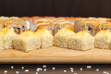 Big sushi set on light wooden dish isolated on black background