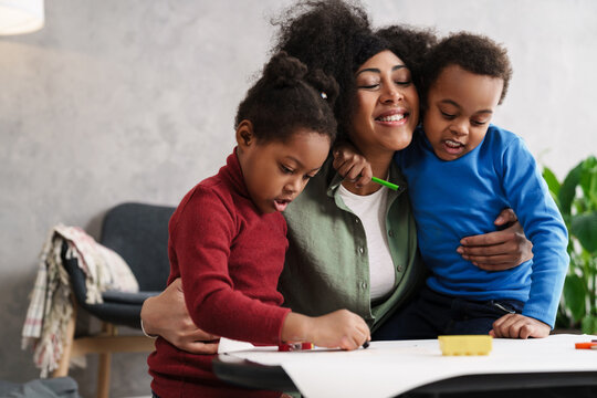 Happy afro american mother hugging while drawing with her children
