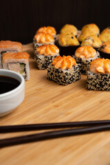 Big sushi set on light wooden dish isolated on black background