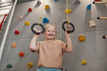 Waist up portrait of cute girl with down syndrome enjoying exercise at home or at sports center and...
