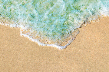 Fototapeta na wymiar Soft waves with foam of blue ocean on the sandy beach