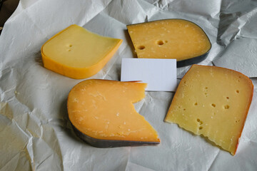 Different kinds of delicious cheeses on waxed wrapping paper. Card mockup. 
