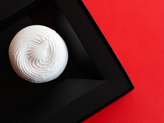 White natural marshmallow in a black box packaging on a red background. A healthy dessert. Baner.