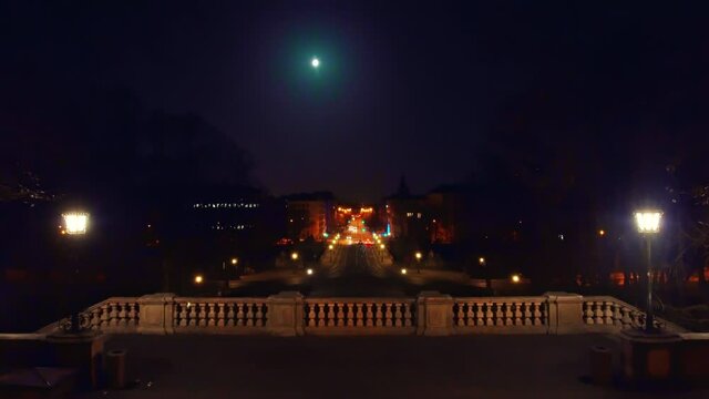 Munich at night - looking over the railing to the straight long Prinzregentenstra&szlig;e with driving cars under the full moon.