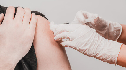 Vaccination close up, injection of vaccine in hand, doctor in white gloves.