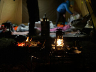 ランプと焚き火の向こうのテントの内部と人影