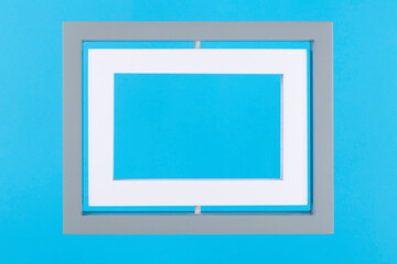 Grey and white double frame on pastel blue background. Minimal border composition