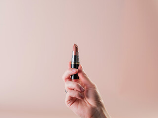 Close-up. Lipstick in the girl's hand. Powdery background