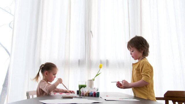 Children drawing with brush in album