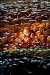 Many kinds of nuts close up. Heap of nuts on a black wooden board. Nuts are stacked on the table. Contrasting dramatic light as an artistic effect.